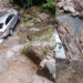 Car Slides Off Wet Road Into Rocky Streambed; Driver Fortunately Survives